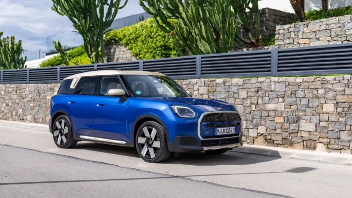 Vue avant du MINI Countryman E en couleur Blazing Blue, montrant les phares LED distinctifs et la grille avant octogonale